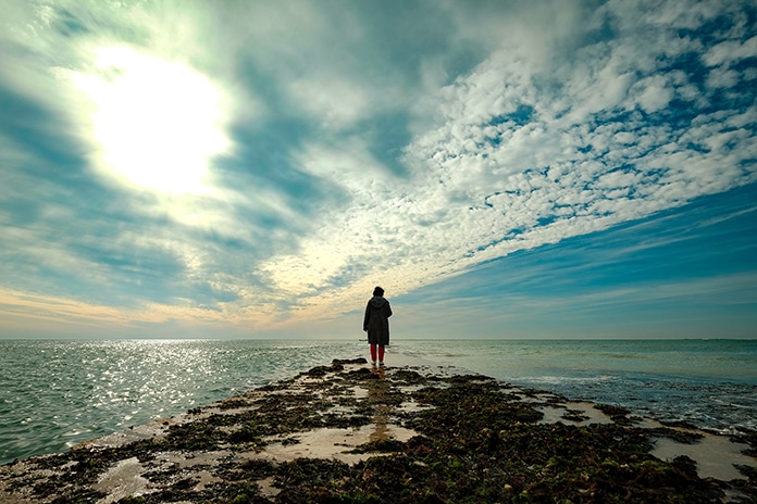 beautiful-shot-person-walking-land-inside-ocean-cloudy-sky